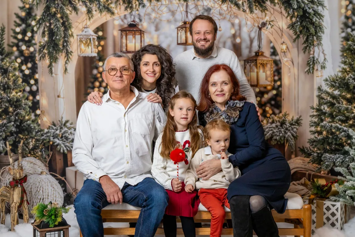 Three generations of one family smiling together under the Christmas arch